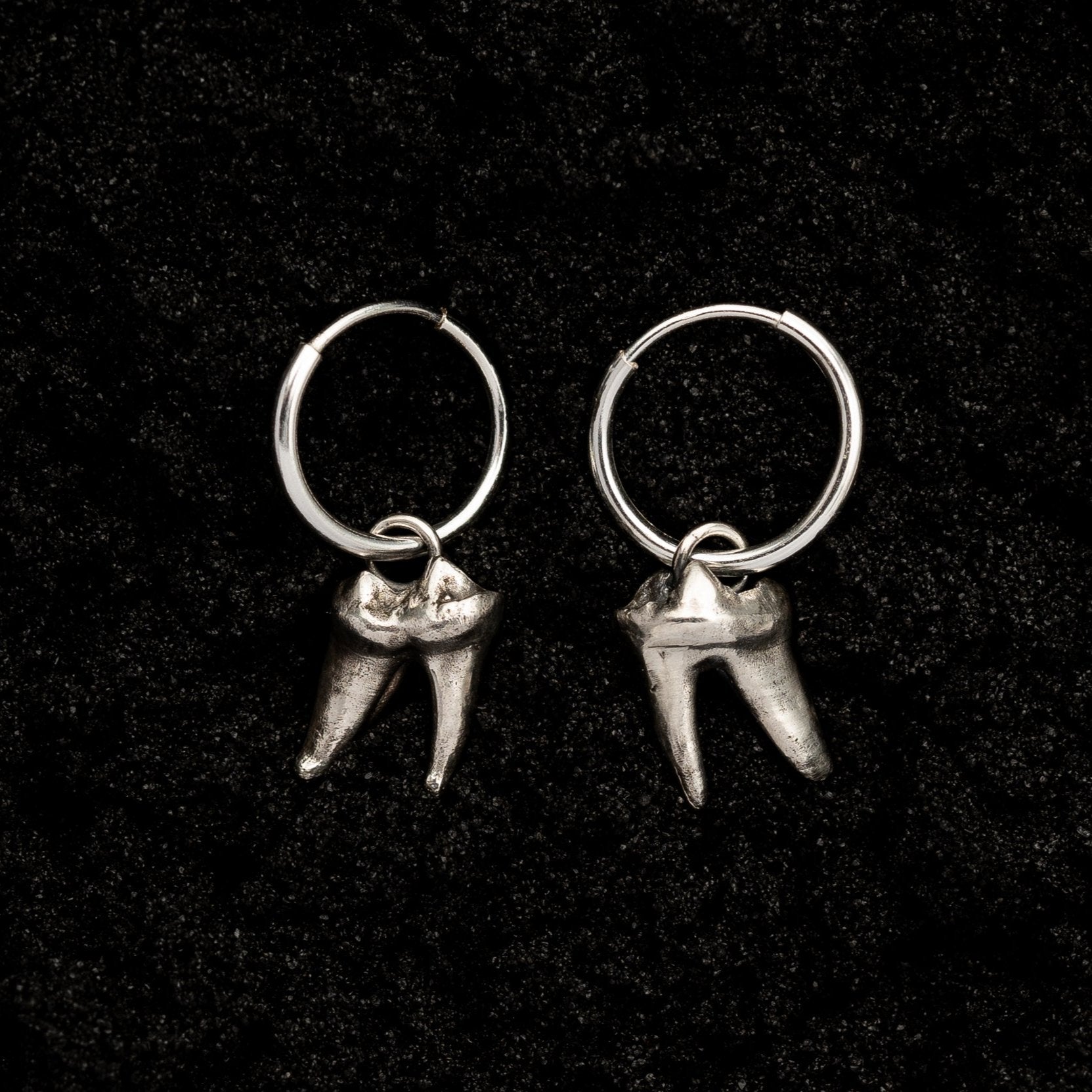 Silver Fox Teeth Hoop Earrings on Black Sand Background